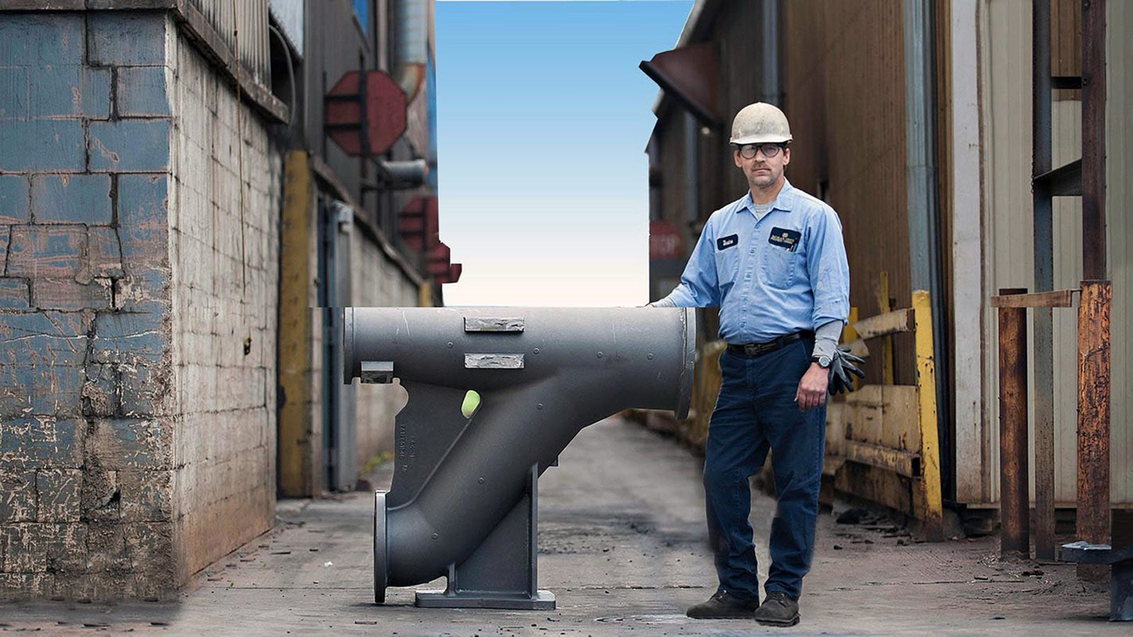 A foundry professional standing beside a large gray-iron casting